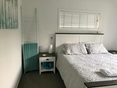een slaapkamer met een bed met een nachtkastje en een raam bij Bar Harbor in Papamoa