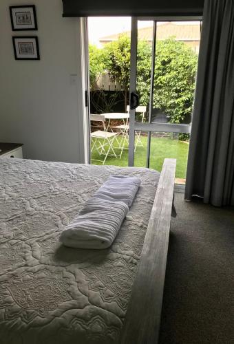 a bed with a pillow on it in a room with a window at Bar Harbor in Papamoa