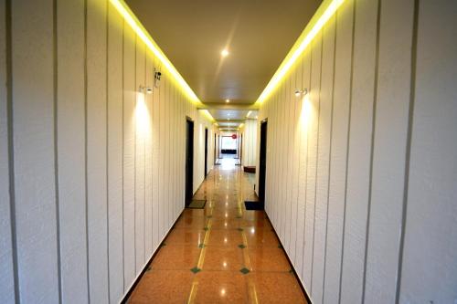 a hallway with white walls and a tile floor and lights at HOTEL SHIV SHAKTI in Bhopal