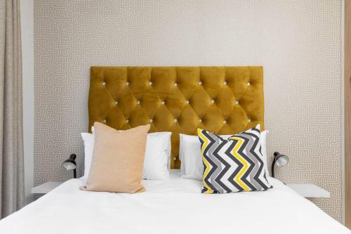 a bed with a yellow headboard and some pillows at Alimama Spaces: The Robert's Greenlee Apartment in Sandown