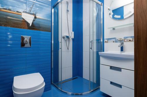 a blue bathroom with a toilet and a shower at VivaLaMer in Pobierowo