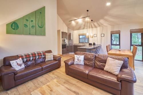 a living room with two leather couches and a kitchen at Host & Stay - Simon Howe Lodge in Whitby