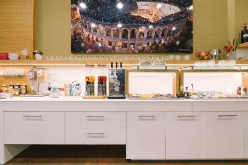a kitchen with a counter with white cabinets at Hotel Giulietta e Romeo ***S in Verona
