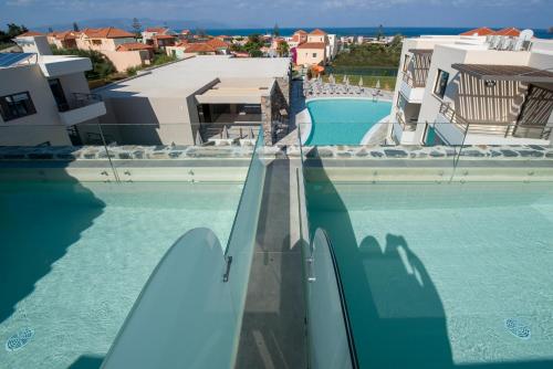 a swimming pool with a slide in the water at Stefan Village Hotel in Agia Marina Nea Kydonias