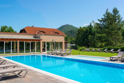 una piscina con sillas y una casa en Honti Apartmanház, en Visegrád