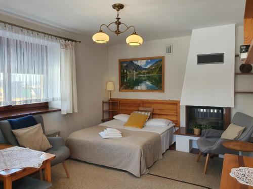 a bedroom with a bed and two chairs and a fireplace at Apartament Iskra in Zakopane