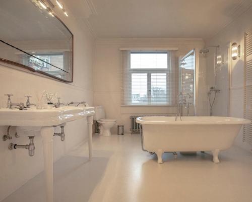 Baño blanco con bañera y lavamanos en ADA, en Amberes