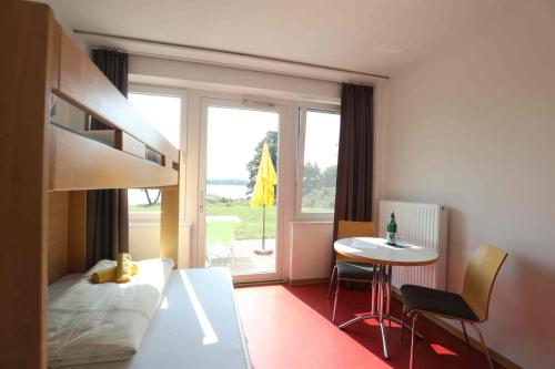 a bedroom with a bed and a table and a window at Jugendherberge Bad Malente in Malente