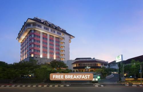 a large building with a free breakfast sign in front of it at Hotel Santika Premiere Semarang in Semarang
