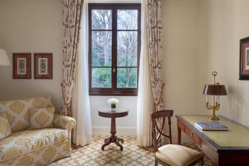 a living room with a couch and a desk and a window at Four Seasons Hotel Firenze in Florence