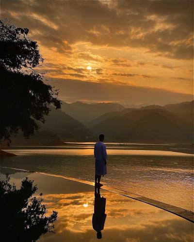 a man walking on the beach near the water at Mai Chau Hideaway Lake Resort in Mai Chau