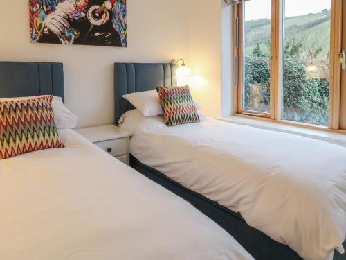 two beds in a room with a window at 2 Garden Apartment in Kingsbridge
