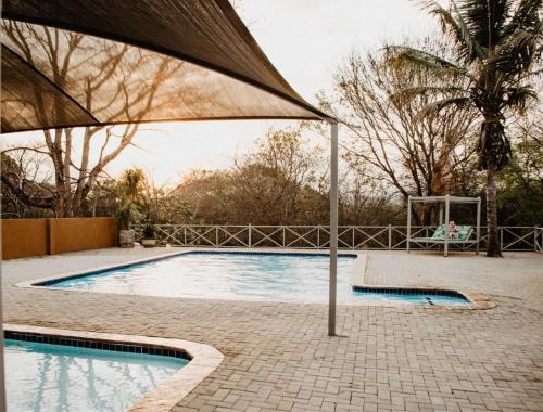 a large swimming pool with a large umbrella at Letaba River Lodge in Tzaneen