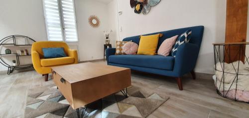 uma sala de estar com um sofá azul e uma cadeira amarela em Maison de ville, Bergerac historique tout à pied em Bergerac