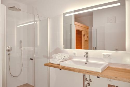 uma casa de banho branca com um lavatório e um chuveiro em die Tauplitz Lodges - Alm Lodge A13 by AA Holiday Homes em Tauplitz