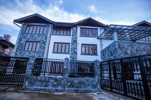 a white house with a black fence in front of it at Seasons Villa - Nuwara Eliya in Nuwara Eliya