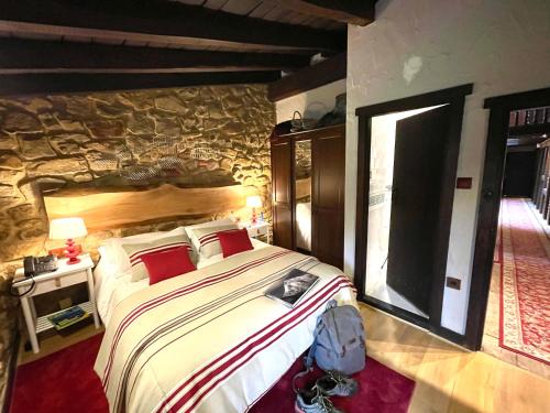 a bedroom with a large bed and a stone wall at MendiGoikoa Bekoa in Axpe