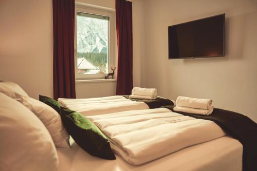 two beds in a room with a tv and a window at die Tauplitz Lodges - Alm Lodge A6 by AA Holiday Homes in Tauplitz