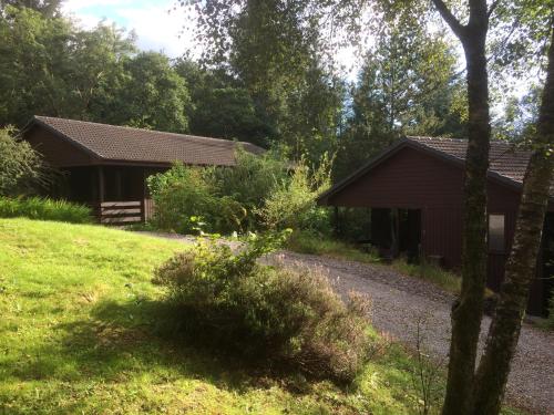 a house in a field with a gravel road in front at Birchbrae Highland Lodges in Onich