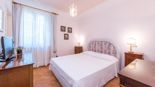 a bedroom with a white bed and a television at BORGO COLLE RIDENTE 13, Emma Villas in Camerino