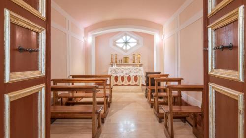 a row of wooden chairs in a church with a altar at BORGO COLLE RIDENTE 13, Emma Villas in Camerino
