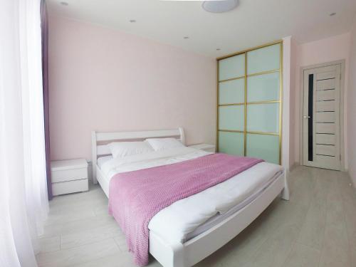 - une chambre avec un lit blanc et une couverture rose dans l'établissement Elite apartments in the center of Lviv, à Lviv