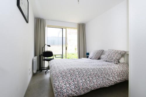 una camera da letto bianca con un letto e una finestra di Heptagone a Saint-Quentin
