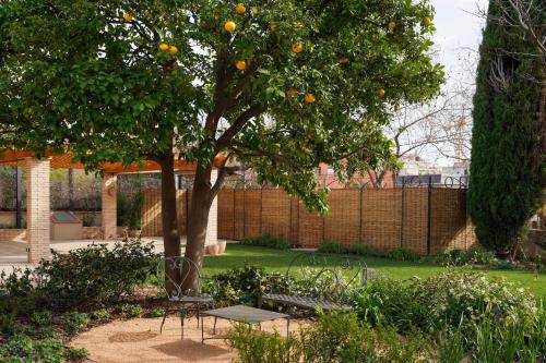 a garden with an orange tree and a table and chairs at Hotel Boutique Mirlo Barcelona in Barcelona