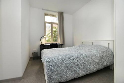 une chambre blanche avec un lit et une fenêtre dans l'établissement Heptagone_1, à Saint-Quentin