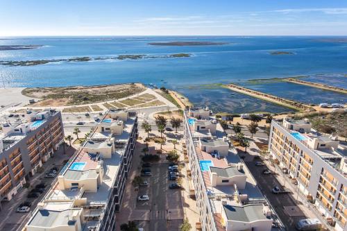 an aerial view of a city and the ocean at Privilege Apartment Les Mouettes with Rooftop Pool, Village Marina - Olhão in Olhão