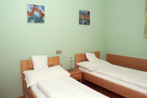 two beds in a room with white sheets at Penzion U Splavu in Břeclav