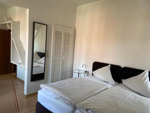 a bedroom with a large white bed with a mirror at Klosterschänke Hude Hotel Ferienwohnungen Restaurant Café in Hude