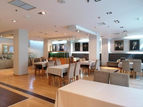 une salle à manger avec des tables et des chaises blanches dans l'établissement Hotel Alexandros, à Anchialos