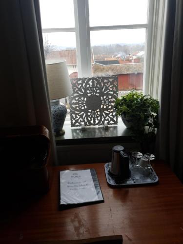 a table with a book and a lamp and a window at Nora Stadshotell, Sure Hotel Collection by Best Western in Nora