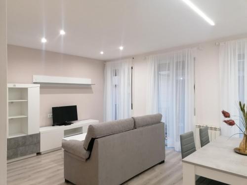 Sala de estar blanca con sofá y TV en Apartamentos El Cid, en Molina de Aragón