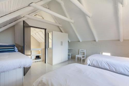 a white room with two beds and a table at Blue Bay Lodge in Saldanha