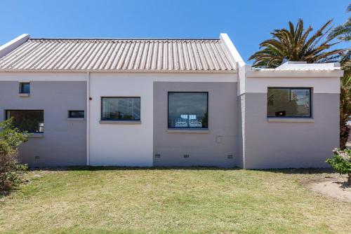 a white house with windows and a palm tree at Blue Bay Lodge in Saldanha