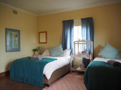 Un dormitorio con dos camas y una ventana. en Riverview Country Inn, en Van Reenen