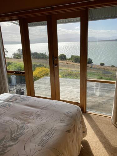 Un dormitorio con una cama y vista al agua. en The Boat Shed, en Sandford