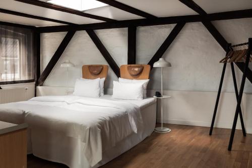 um quarto com uma cama grande e lençóis brancos em Hotel SP34 by Brøchner Hotels em Copenhague