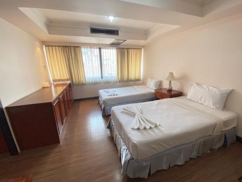 a hotel room with two beds and a desk at Jumbotel Hotel in Bangkok