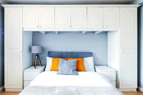 Schlafzimmer mit einem Bett mit weißen Schränken und orangefarbenen Kissen in der Unterkunft Eagle Drive in Hendon