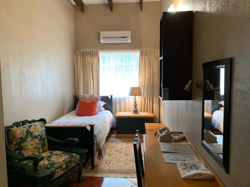 a bedroom with a bed and a chair and a window at Jelani Guest House in White River