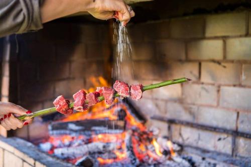 a person cooking meat on a stick over a fire at Funchal Center Apartment II in Funchal