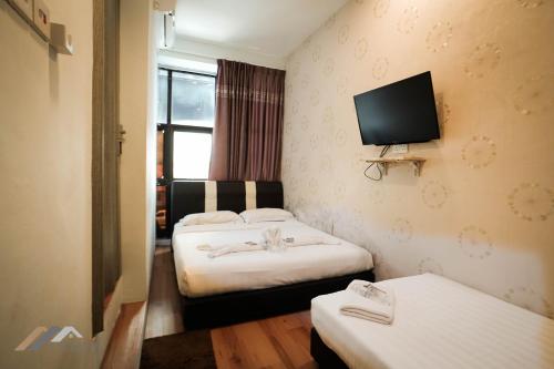 a hotel room with two beds and a flat screen tv at Welcome Inn by Evernent @ Pelita Commercial, Miri in Miri