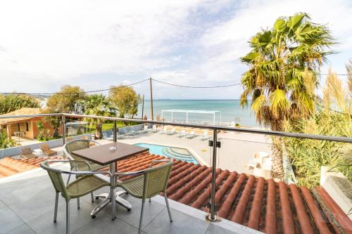 a balcony with a table and chairs and the ocean at SunRose Beach Aparthotel in Acharavi