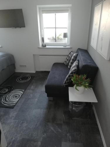 a living room with a black couch and a table at Ferienwohnung Hirmer in Zirndorf