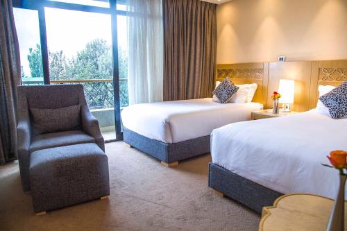 a hotel room with two beds and a chair at Vamos Addis Hotel in Addis Ababa