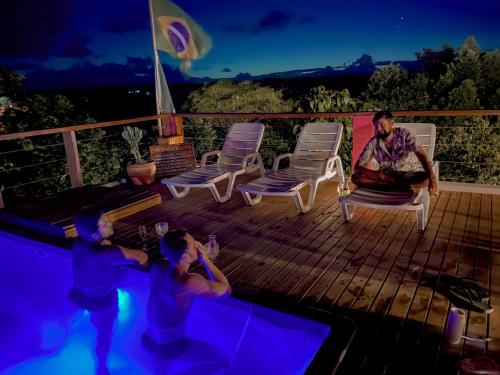un hombre y dos niños sentados en una terraza junto a una piscina en Vila Real Apartamentos en Itacaré