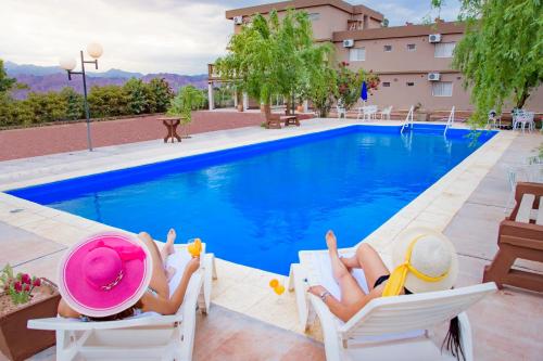 two people laying in chairs next to a swimming pool at Hotel Cuesta de Miranda in Villa Unión